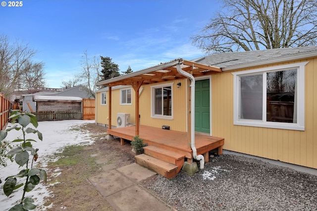 snow covered rear of property with a deck and ac unit