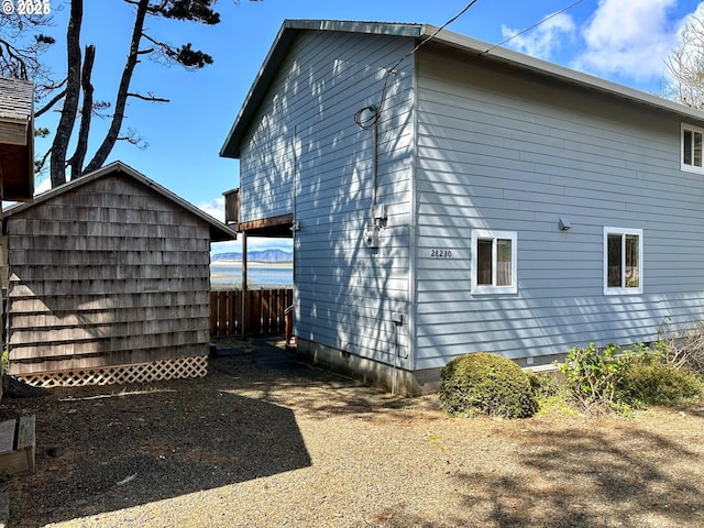 26230 Sandlake Rd, Cloverdale, OR 97112 - view of side of home with an outdoor structure, a shed, and fence