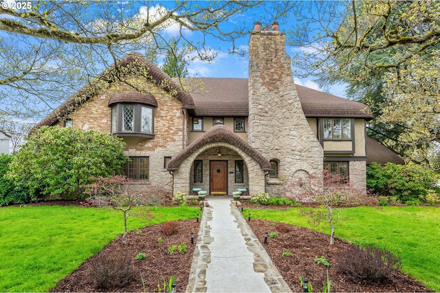 6633 SE 29th Ave, Portland, OR 97202 - tudor home featuring a chimney, a front lawn, roof with shingles, and stone siding