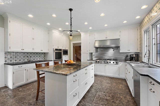 6633 SE 29th Ave, Portland, OR 97202 - kitchen with a sink, decorative backsplash, under cabinet range hood, a kitchen island, and appliances with stainless steel finishes