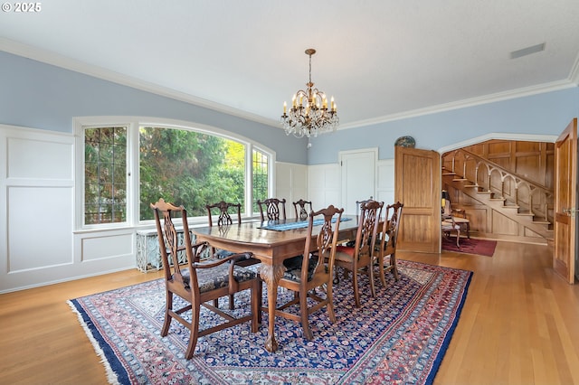 6633 SE 29th Ave, Portland, OR 97202 - dining area with wood finished floors, a decorative wall, stairs, and an inviting chandelier
