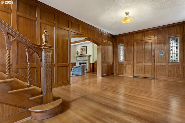 6633 SE 29th Ave, Portland, OR 97202 - entryway featuring stairs, a textured ceiling, light wood-style flooring, a fireplace, and wood walls