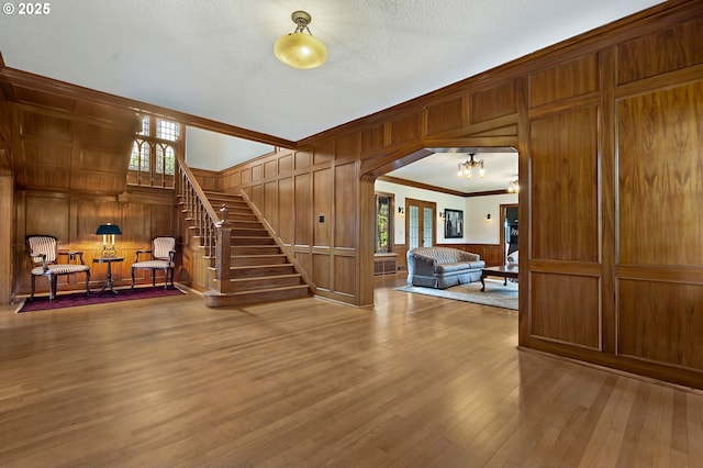 6633 SE 29th Ave, Portland, OR 97202 - unfurnished living room featuring ornamental molding, wood finished floors, wood walls, and stairway