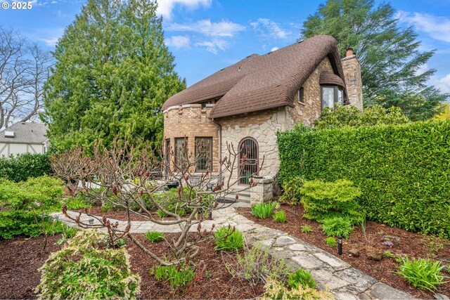 6633 SE 29th Ave, Portland, OR 97202 - tudor home featuring stone siding, a shingled roof, and a chimney