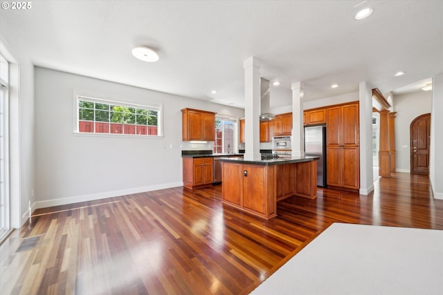 13733 NW Trevino St, Portland, OR 97229 - kitchen featuring appliances with stainless steel finishes, dark wood-type flooring, brown cabinets, a center island, and recessed lighting