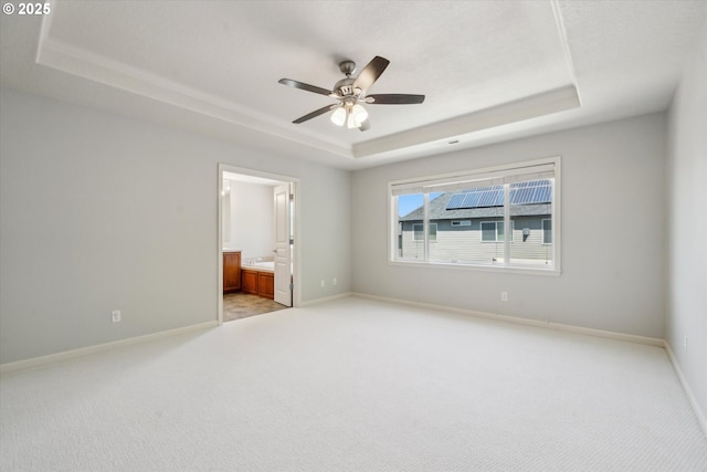 13733 NW Trevino St, Portland, OR 97229 - unfurnished bedroom with a tray ceiling, light colored carpet, baseboards, ensuite bathroom, and a ceiling fan