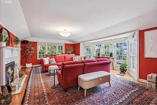 4317 SW Bernard Dr, Portland, OR 97239 - living room with vaulted ceiling, light wood-style floors, a glass covered fireplace, and baseboards