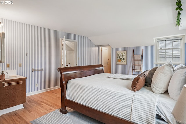 4317 SW Bernard Dr, Portland, OR 97239 - bedroom with light wood-style flooring, wallpapered walls, baseboards, lofted ceiling, and a sink