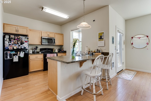 443/447 E 16th Ave, Eugene, OR 97401 - kitchen with black appliances, light brown cabinetry, dark countertops, a peninsula, and light wood-type flooring
