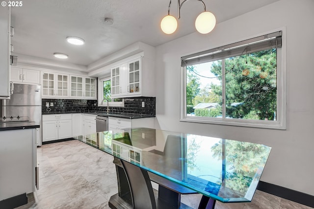 kitchen with dark countertops, white cabinets, and backsplash