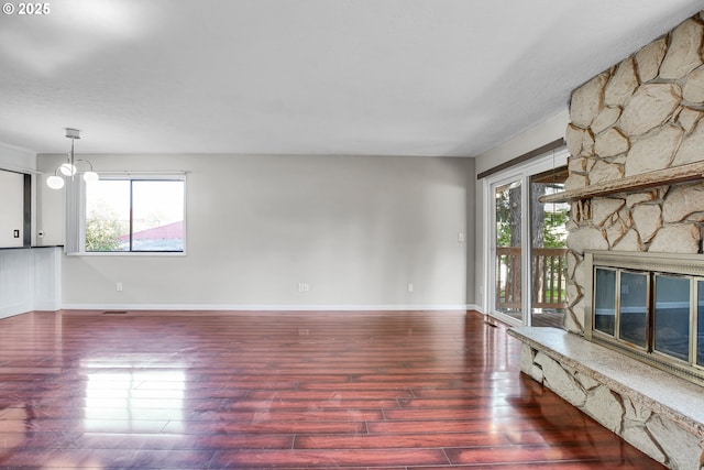 unfurnished living room featuring baseboards, plenty of natural light, wood finished floors, and a fireplace