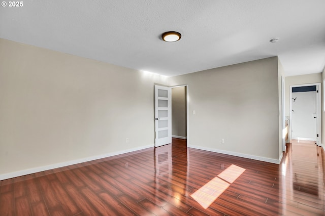 spare room featuring baseboards and wood finished floors