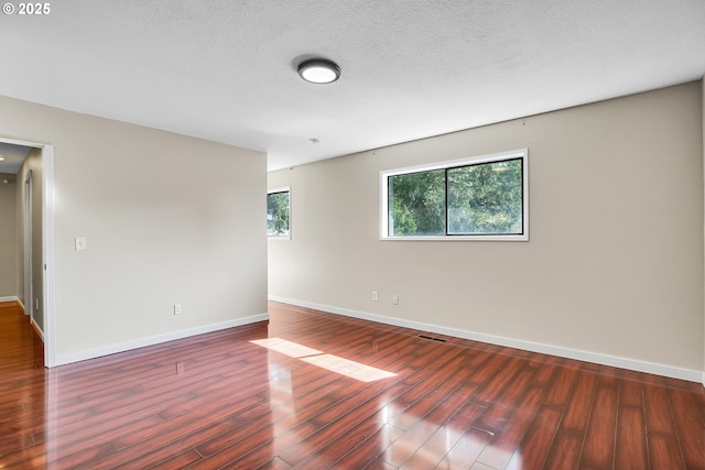 spare room with baseboards, wood finished floors, and visible vents