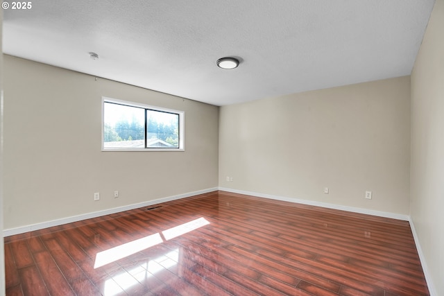 unfurnished room featuring baseboards, a textured ceiling, and wood finished floors