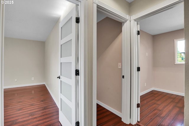 corridor featuring baseboards and wood finished floors