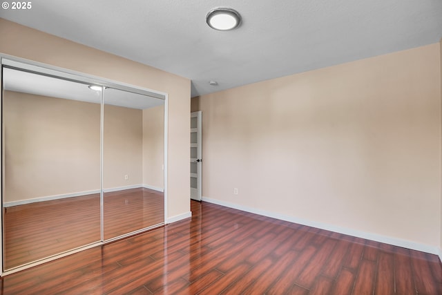 unfurnished bedroom with baseboards, wood finished floors, and a closet