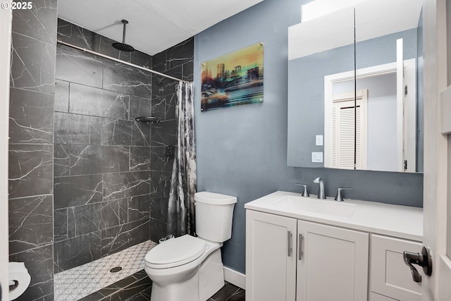 bathroom with toilet, tiled shower, and vanity
