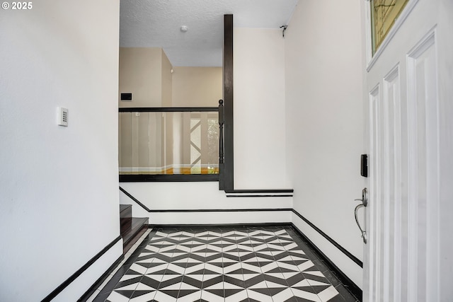 entrance foyer featuring tile patterned floors, baseboards, and a textured ceiling