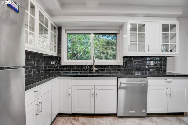 kitchen featuring a sink, tasteful backsplash, stainless steel appliances, and white cabinets