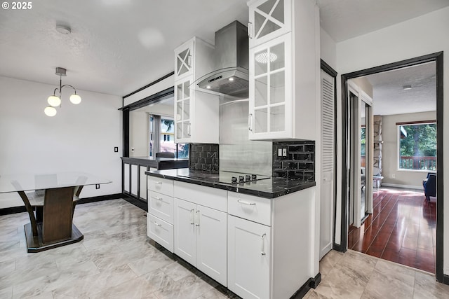 kitchen with decorative backsplash, wall chimney exhaust hood, dark countertops, and white cabinetry