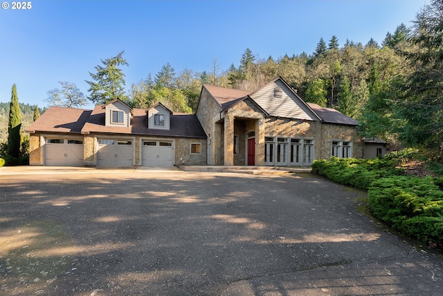 view of front facade featuring stone siding, an attached garage, and driveway