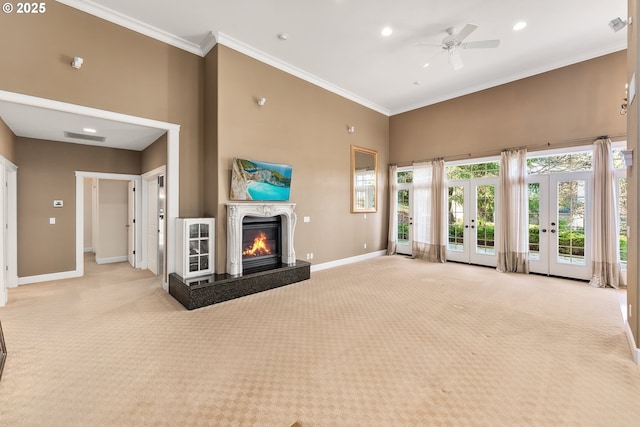 unfurnished living room featuring baseboards, carpet flooring, french doors, a glass covered fireplace, and a ceiling fan
