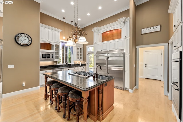 kitchen featuring built in appliances, ornamental molding, a kitchen breakfast bar, recessed lighting, and a kitchen island with sink