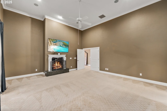 unfurnished living room with a warm lit fireplace, light colored carpet, visible vents, baseboards, and ornamental molding