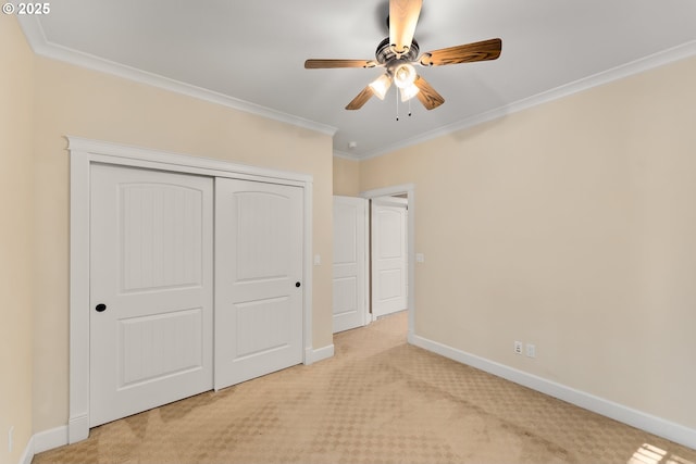 unfurnished bedroom featuring carpet, baseboards, crown molding, a closet, and a ceiling fan