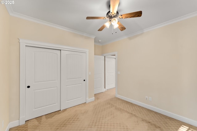 unfurnished bedroom featuring carpet floors, a ceiling fan, baseboards, a closet, and crown molding