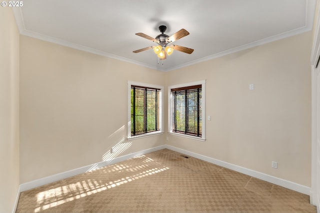 unfurnished room with carpet floors, baseboards, crown molding, and a ceiling fan