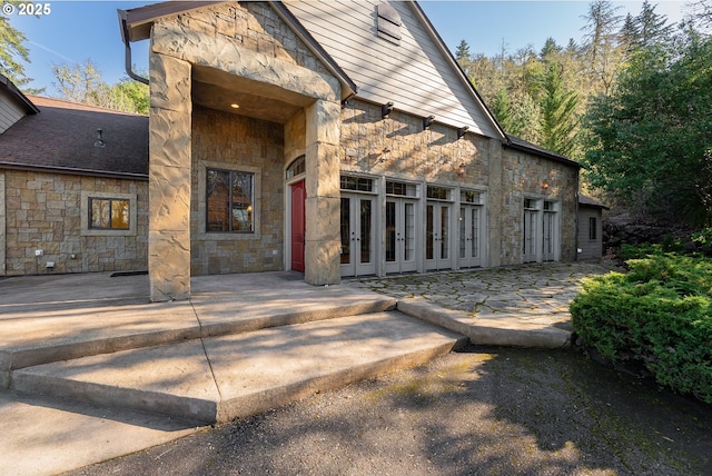 view of exterior entry featuring stone siding, french doors, and a patio area