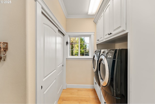 laundry area with washing machine and dryer, baseboards, ornamental molding, cabinet space, and light wood-style floors