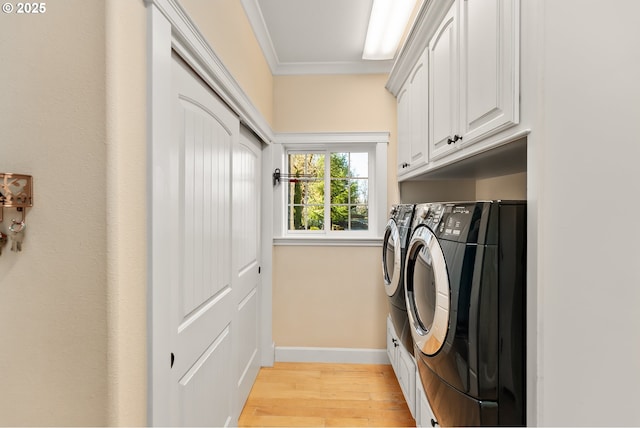 laundry area with light wood finished floors, cabinet space, baseboards, ornamental molding, and independent washer and dryer