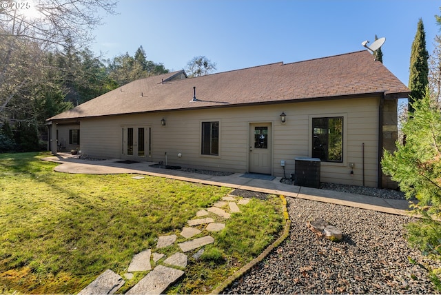 rear view of property with french doors, a patio, central air condition unit, a shingled roof, and a lawn