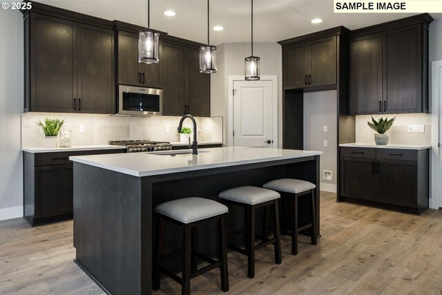 4688 NW 71st Ave, Camas, WA 98607 - kitchen with stainless steel appliances, decorative backsplash, light wood-style floors, dark brown cabinetry, and under cabinet range hood