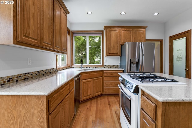 17811 NW Gilbert Ln, Portland, OR 97229 - kitchen featuring appliances with stainless steel finishes, a sink, light wood finished floors, brown cabinets, and backsplash