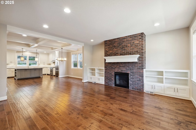 2760 SW Sylvania Ter, Portland, OR 97219 - unfurnished living room featuring dark wood-style flooring, recessed lighting, a brick fireplace, beamed ceiling, and coffered ceiling