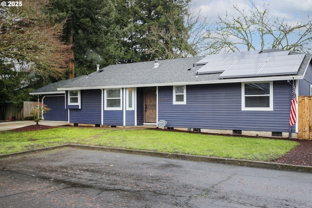 view of front of home featuring a garage, a front lawn, and solar panels