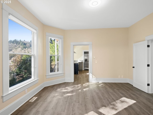 spare room with baseboards, visible vents, and wood finished floors