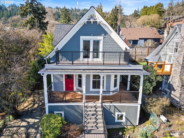 view of front of house featuring a porch, a shingled roof, stairway, fence, and a balcony