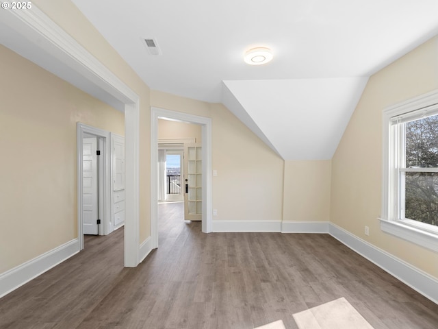 additional living space featuring lofted ceiling, visible vents, baseboards, and wood finished floors