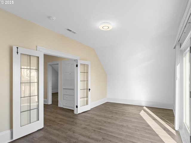 bonus room with baseboards, visible vents, vaulted ceiling, and wood finished floors