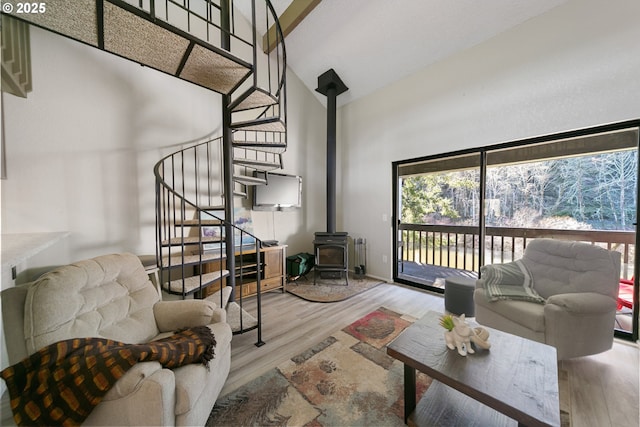 43605 State Highway 38 Unit 9, Reedsport, OR 97467 - living area featuring high vaulted ceiling, stairway, a wood stove, wood finished floors, and radiator heating unit