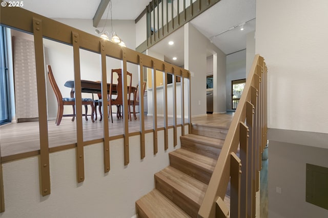 43605 State Highway 38 Unit 9, Reedsport, OR 97467 - staircase with wood finished floors, a towering ceiling, rail lighting, a chandelier, and baseboards