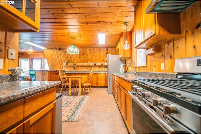 5920 Elkhead Rd, Yoncalla, OR 97499 - kitchen featuring stainless steel appliances, wooden walls, ventilation hood, brown cabinetry, and pendant lighting