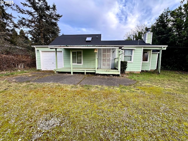 rear view of property featuring a garage and a chimney