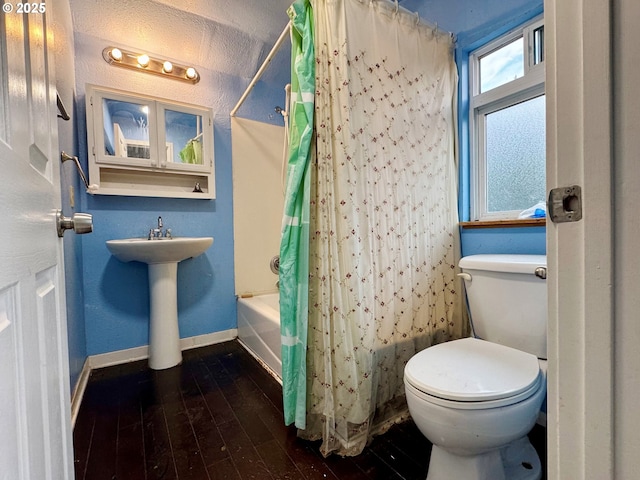 full bathroom with toilet, shower / bath combo, baseboards, and wood finished floors