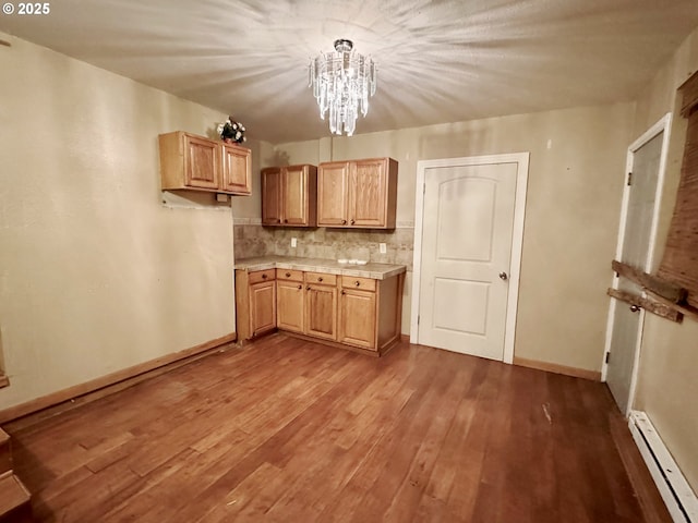 kitchen with a baseboard radiator, baseboards, light countertops, decorative backsplash, and hardwood / wood-style floors