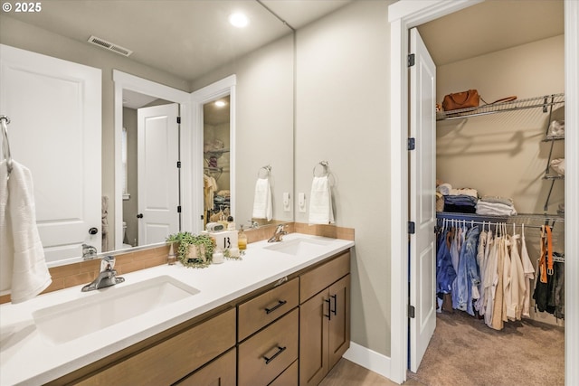 bathroom featuring a spacious closet, a sink, and visible vents